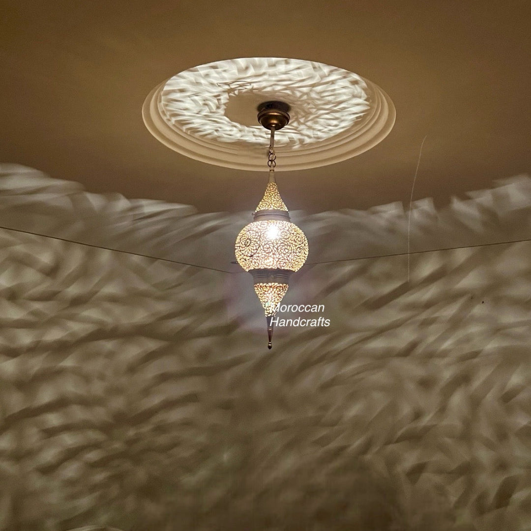 Close-up of a hand-engraved Fez-style lantern suspended below a decorative ceiling medallion.