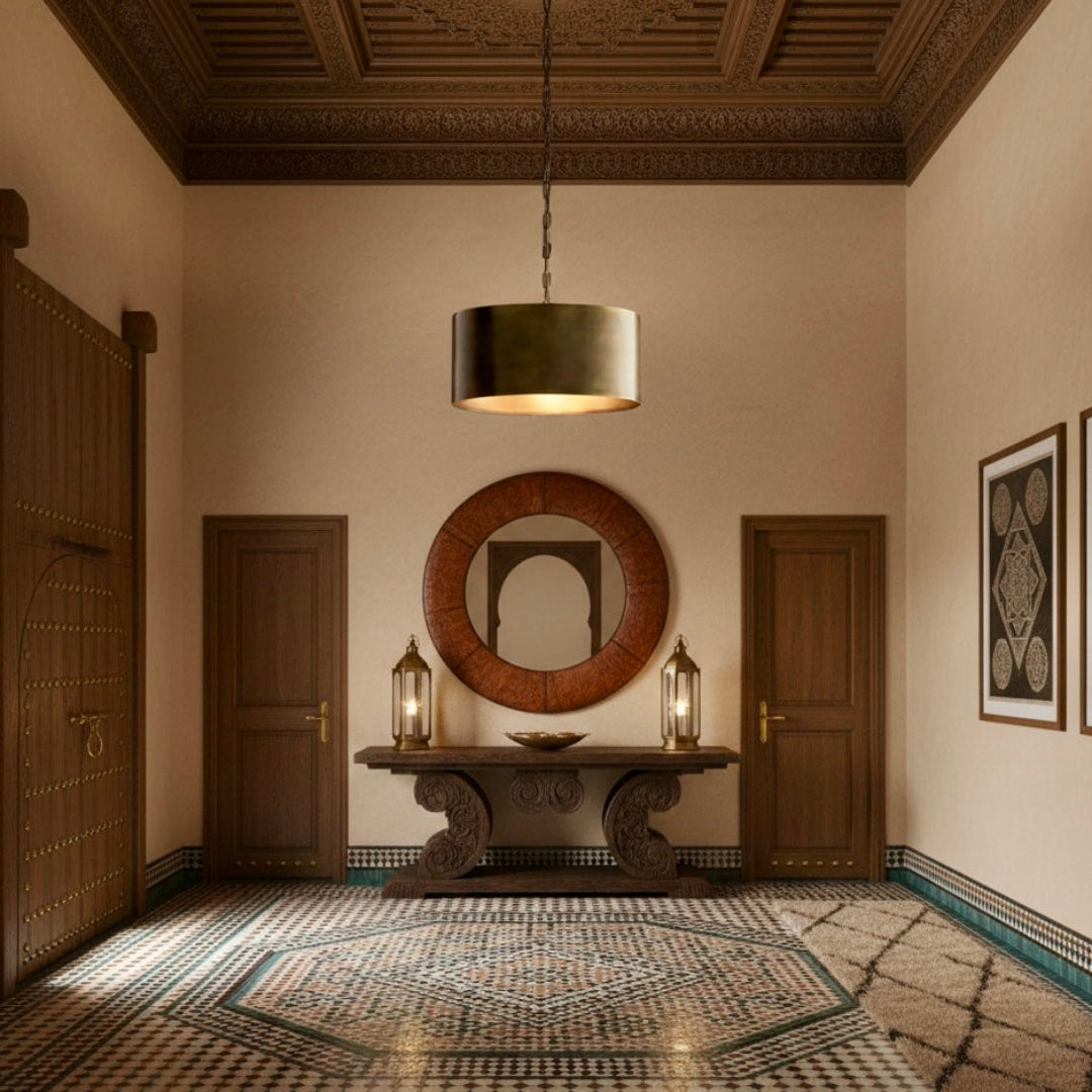 Single brass drum pendant light in a traditional Moroccan entryway with zellige tile flooring and carved wood ceilings.