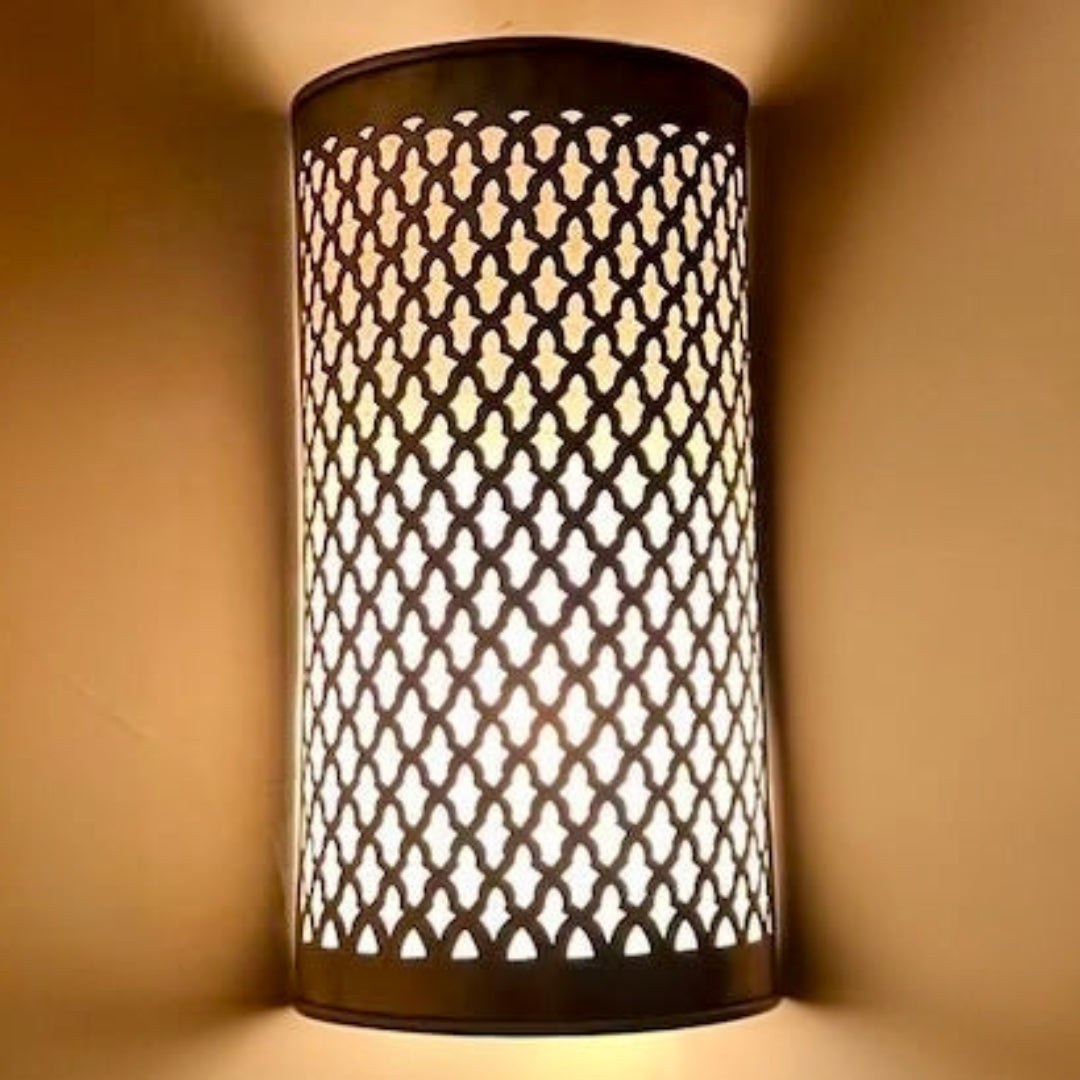Moroccan brass wall lamp lit up to create beautiful geometric shadows on a neutral wall, perfect for a modern luxury hotel aesthetic.