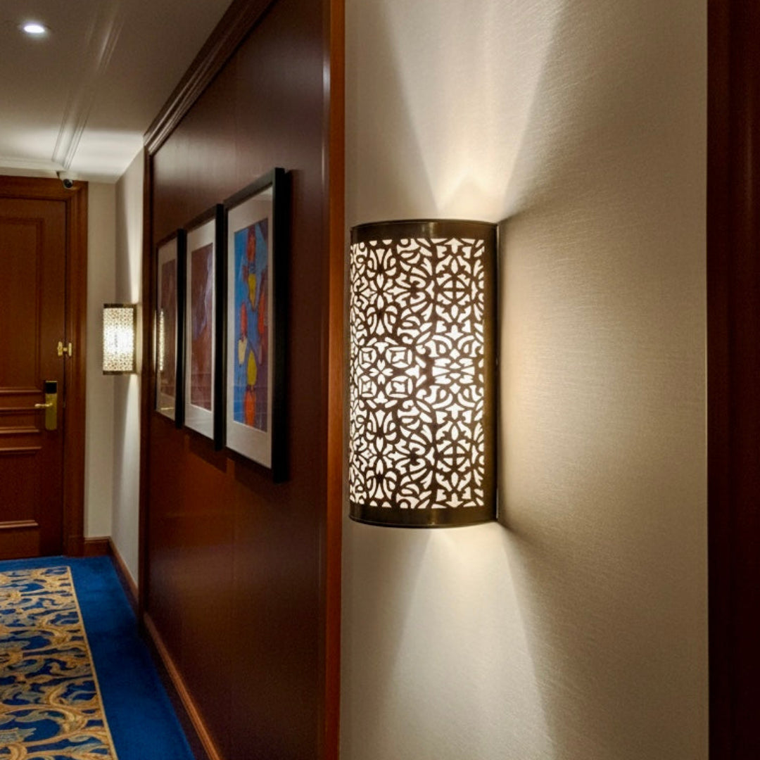 Luxurious handmade brass wall sconce in a Moroccan style hallway, providing elegant ambient lighting.