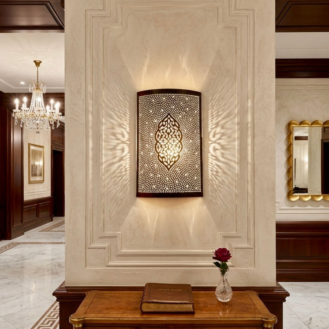 Elegant Moroccan brass wall sconce mounted on a decorative indoor pillar in a luxury hallway, featuring intricate handmade engravings and warm ambient lighting.
