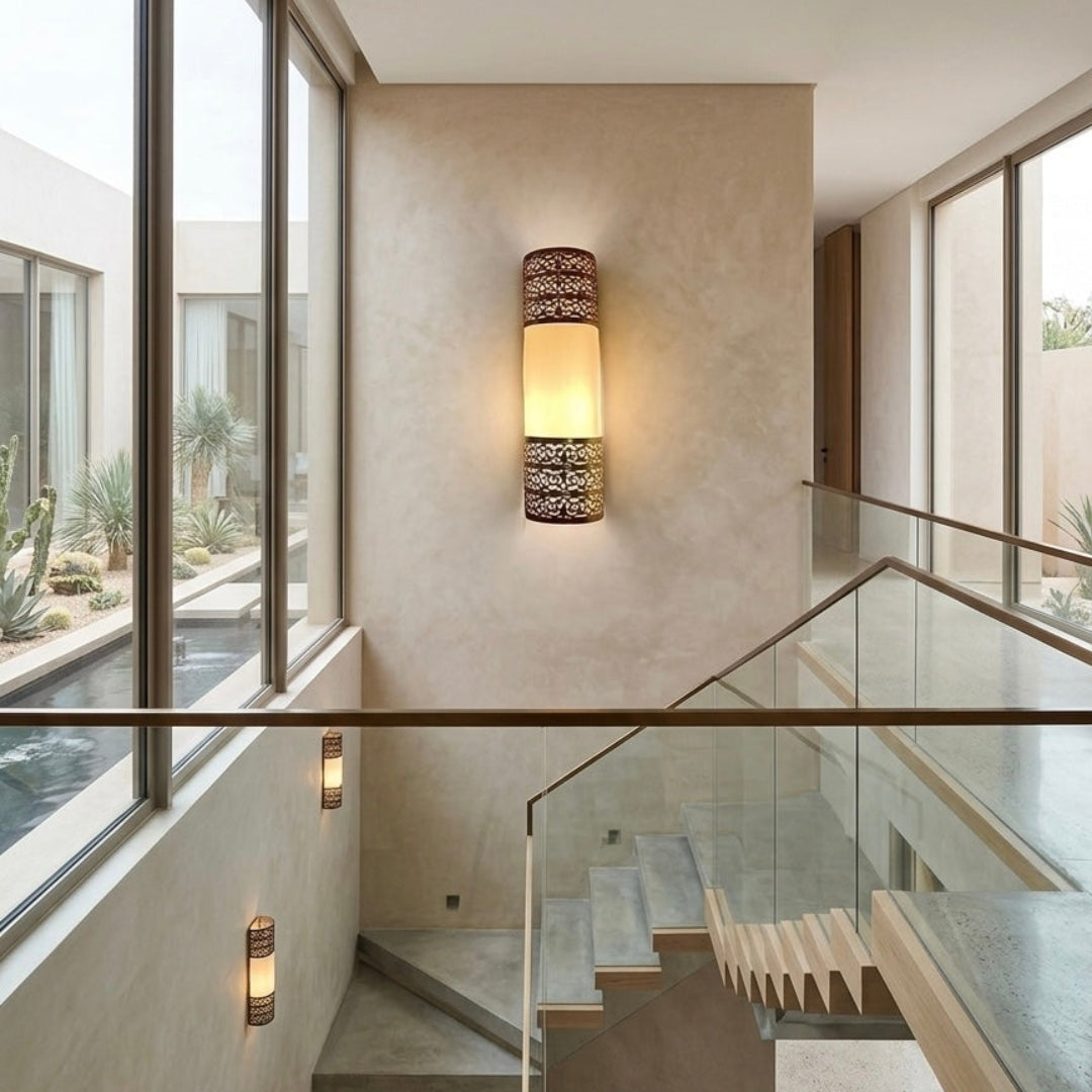 Multiple handmade Moroccan brass sconces illuminating a modern minimalist staircase with large glass windows and desert view.