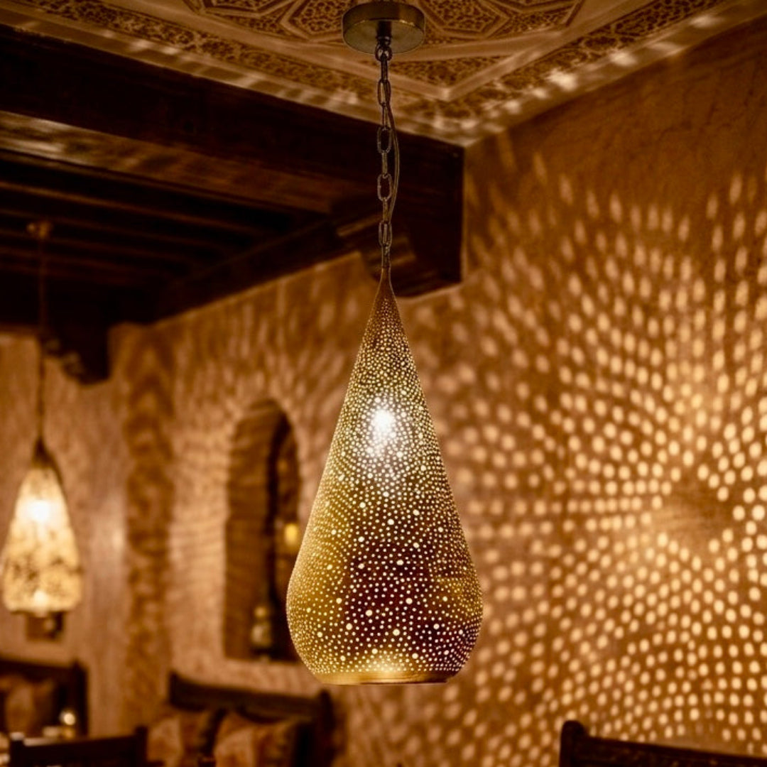 Close-up of a Moroccan perforated brass pendant projecting beautiful geometric light patterns on a textured wall.