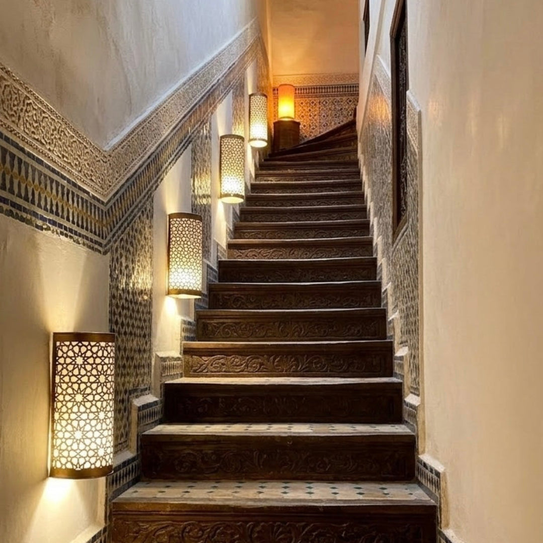 Authentic Moroccan brass wall sconces installed along a traditional tiled staircase in a Marrakech riad.