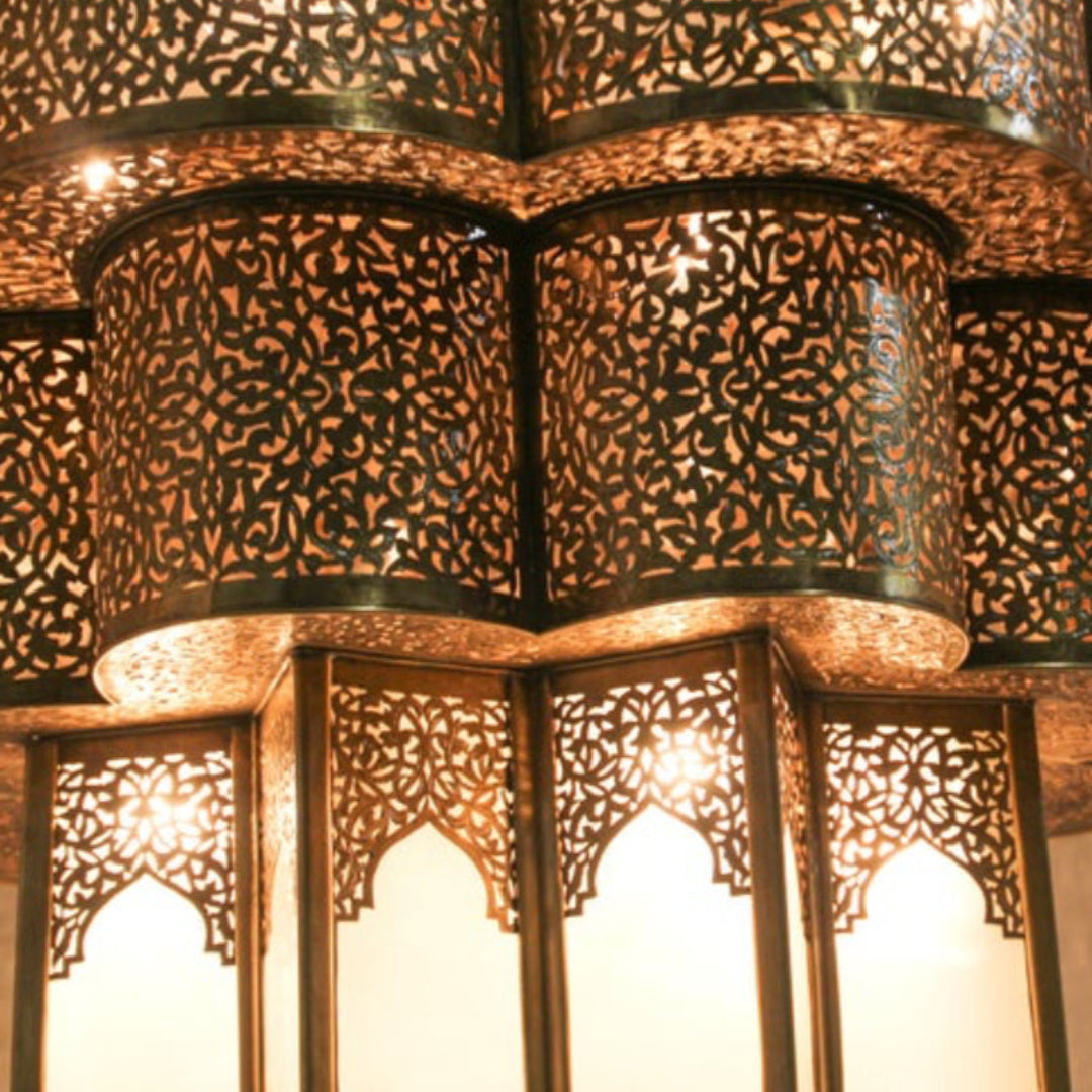 Close-up of reticulated Moorish metalwork, highlighting the shadow casting geometric patterns on the wall.