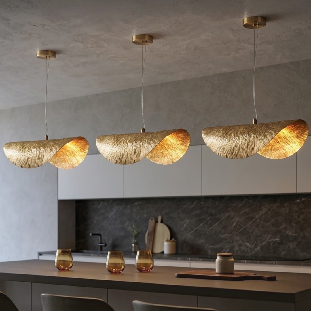 Three modern Moroccan brass pendant lights hanging over a dark marble kitchen island in a minimalist contemporary interior
