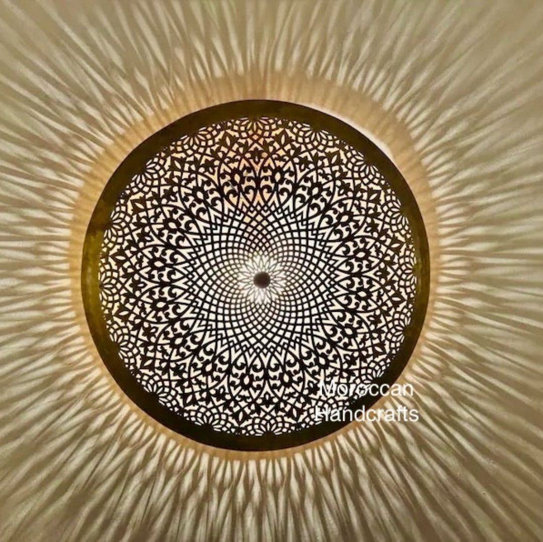 Close-up of a traditional Moroccan lamp (flush mount) creating a bright, radiant, sunburst light effect.