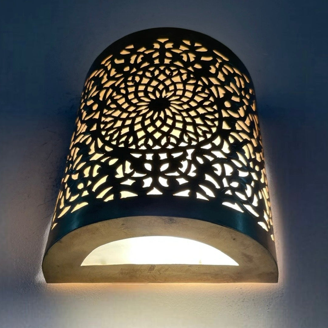 Close-up of authentic Moroccan hand-etched brass wall light with gold finish.