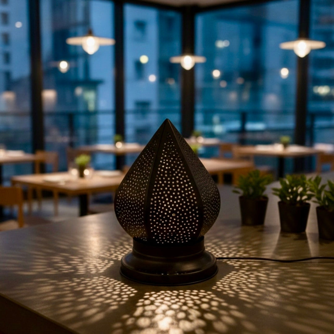 Moroccan filigree table lamp on a wooden bedside table providing warm ambient lighting.