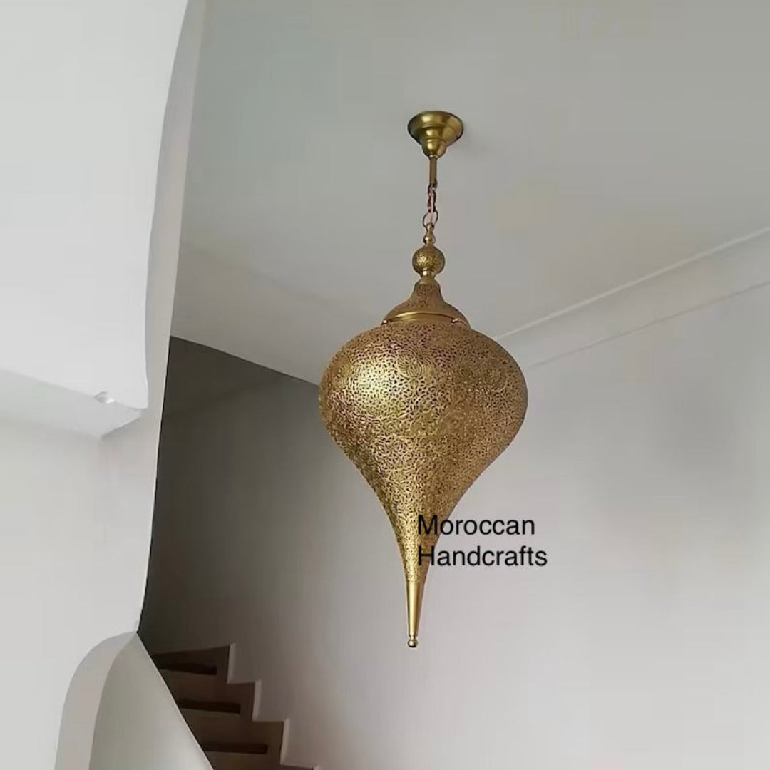 Traditional Arabic-style brass chandelier casting dramatic shadow patterns above a small carved wooden tea table.