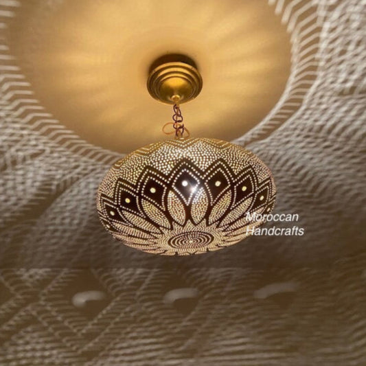 Handcrafted circular brass Moroccan wall sconce with intricate geometric piercing, casting a dramatic starburst light pattern on a textured wall.