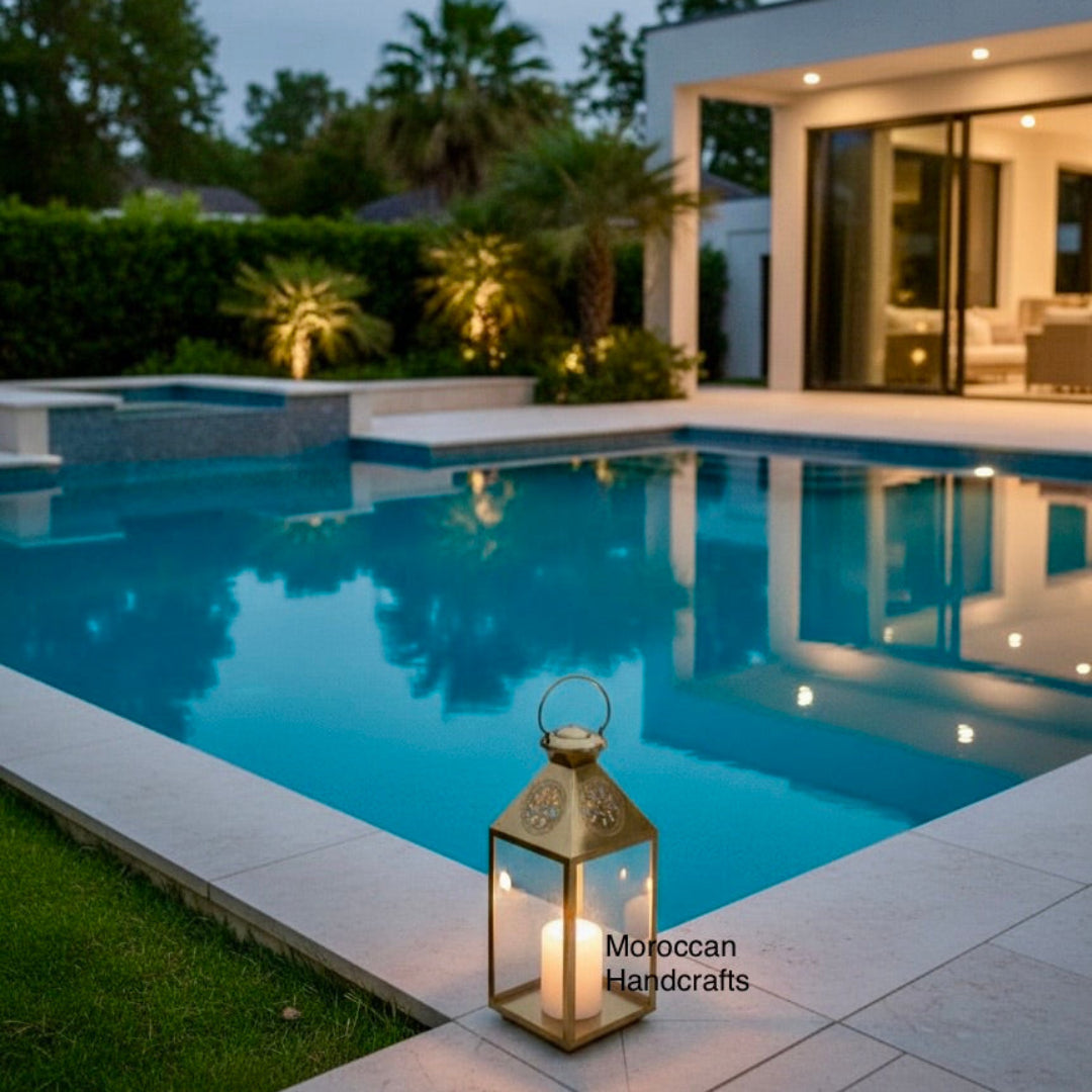 Detailed shot of a sophisticated brass lantern with a handle and decorative hand-engraving near the top, used as a centerpiece with a burning candle.