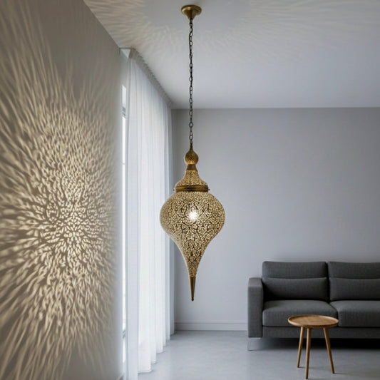 Handmade Moroccan brass pendant lamp casting intricate floral shadow patterns on a dining room wall.