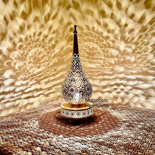 Close-up of a handcrafted Moroccan brass table lamp with intricate geometric cut-outs.