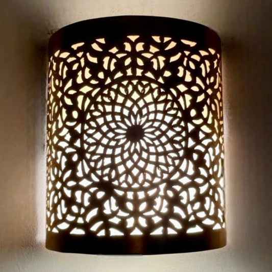 Wall mounted handmade brass Moroccan sconce casting intricate light patterns.