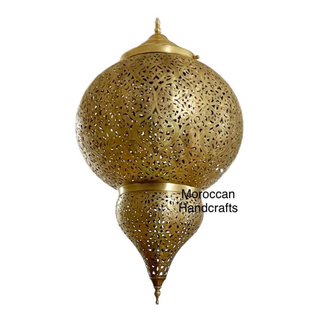 Close-up of a large, teardrop-shaped handmade Moroccan brass lantern (Fanoos) hanging from a ceiling medallion.