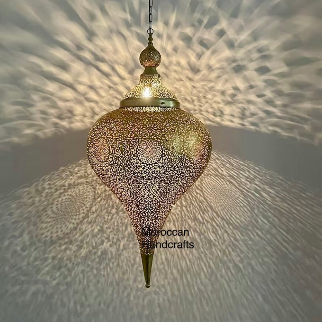 Large, handcrafted Moroccan teardrop-shaped brass pendant light casting intricate shadow patterns on a cream-colored ceiling and walls.