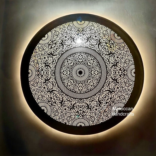 Round Moroccan brass wall sconce with dense, intricate floral and geometric filigree design.