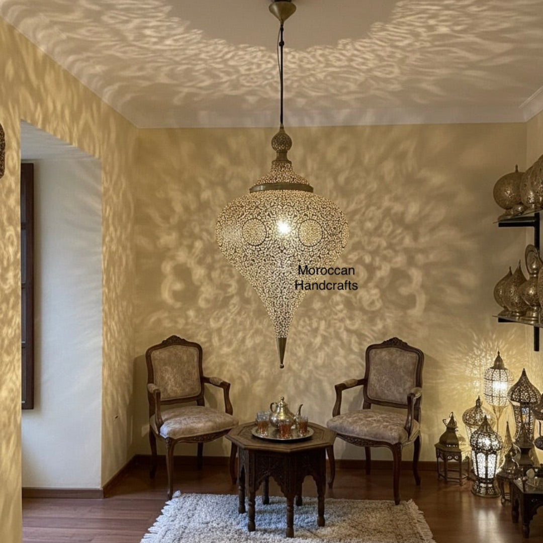 Full view of a Moroccan-style living area featuring a central filigree brass ceiling lamp, two velvet armchairs, and a carved wooden side table 