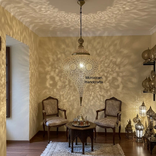 Full view of a Moroccan-style living area featuring a central filigree brass ceiling lamp, two velvet armchairs, and a carved wooden side table 