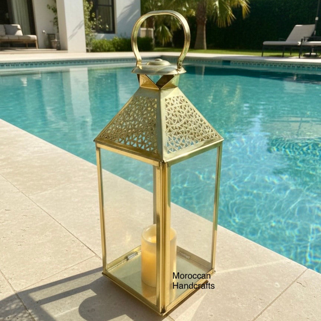 Moroccan style brass lantern used as decorative lighting, creating a warm glow through traditional metalwork patterns.