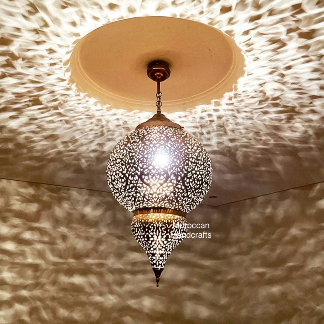 Hand-pierced brass Moroccan filigree pendant light casting intricate star patterns on a warm-toned ceiling.