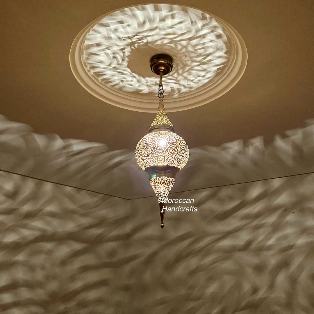 Vintage-look perforated brass pendant lamp creating a focused beam of patterned light and shadow on the walls.
