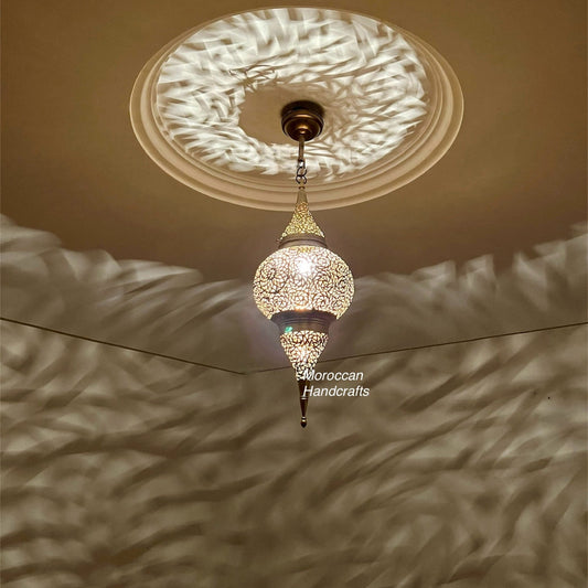 Vintage-look perforated brass pendant lamp creating a focused beam of patterned light and shadow on the walls.