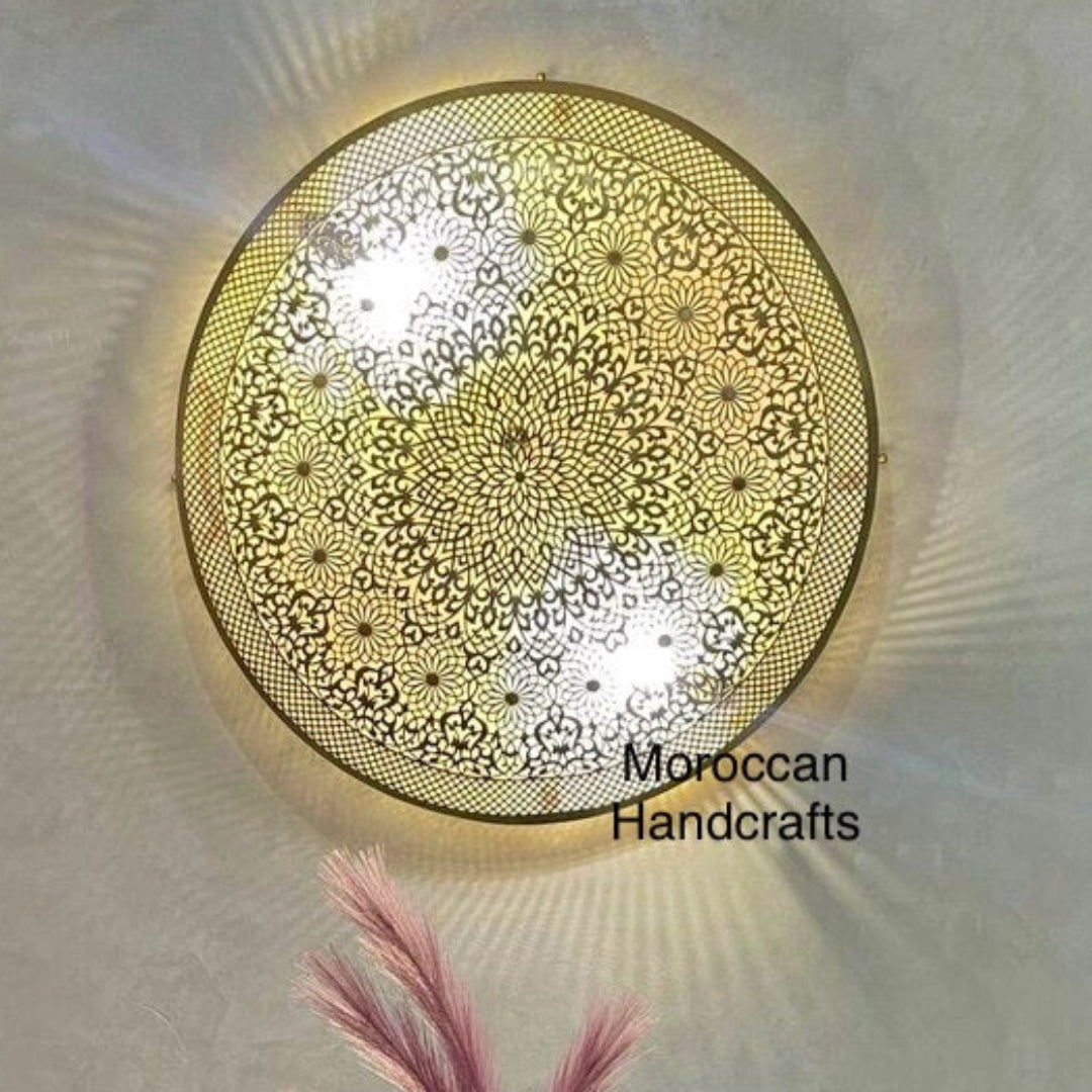 Round Moroccan brass sconce casting dramatic radial sunburst shadow patterns on the surrounding wall.