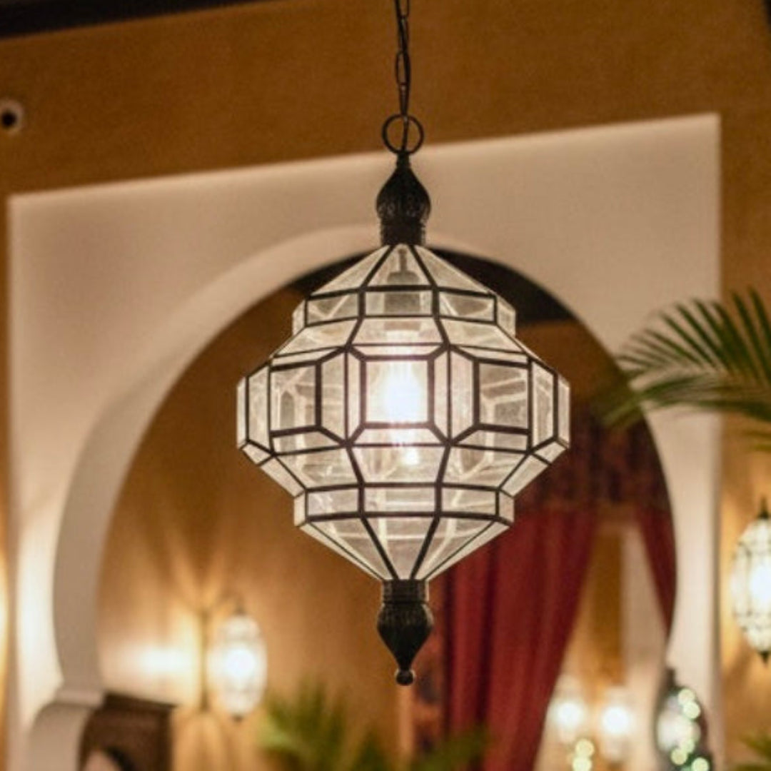  Detailed view of the geometric glass and brass frame of a Moroccan hanging light fixture.