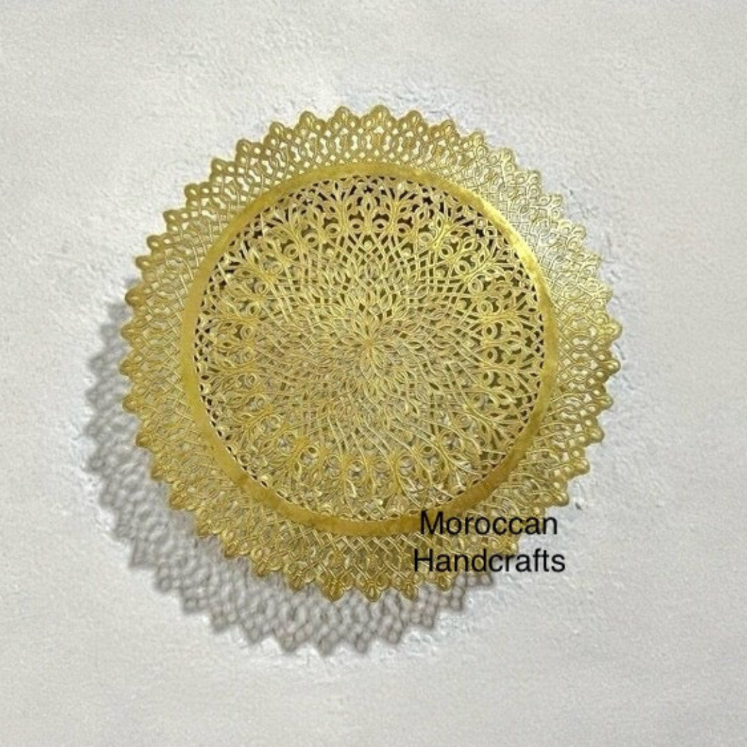 Dark brass Moroccan wall lamp with scalloped outer edges and a central filigree pattern, casting strong radial shadow effects.