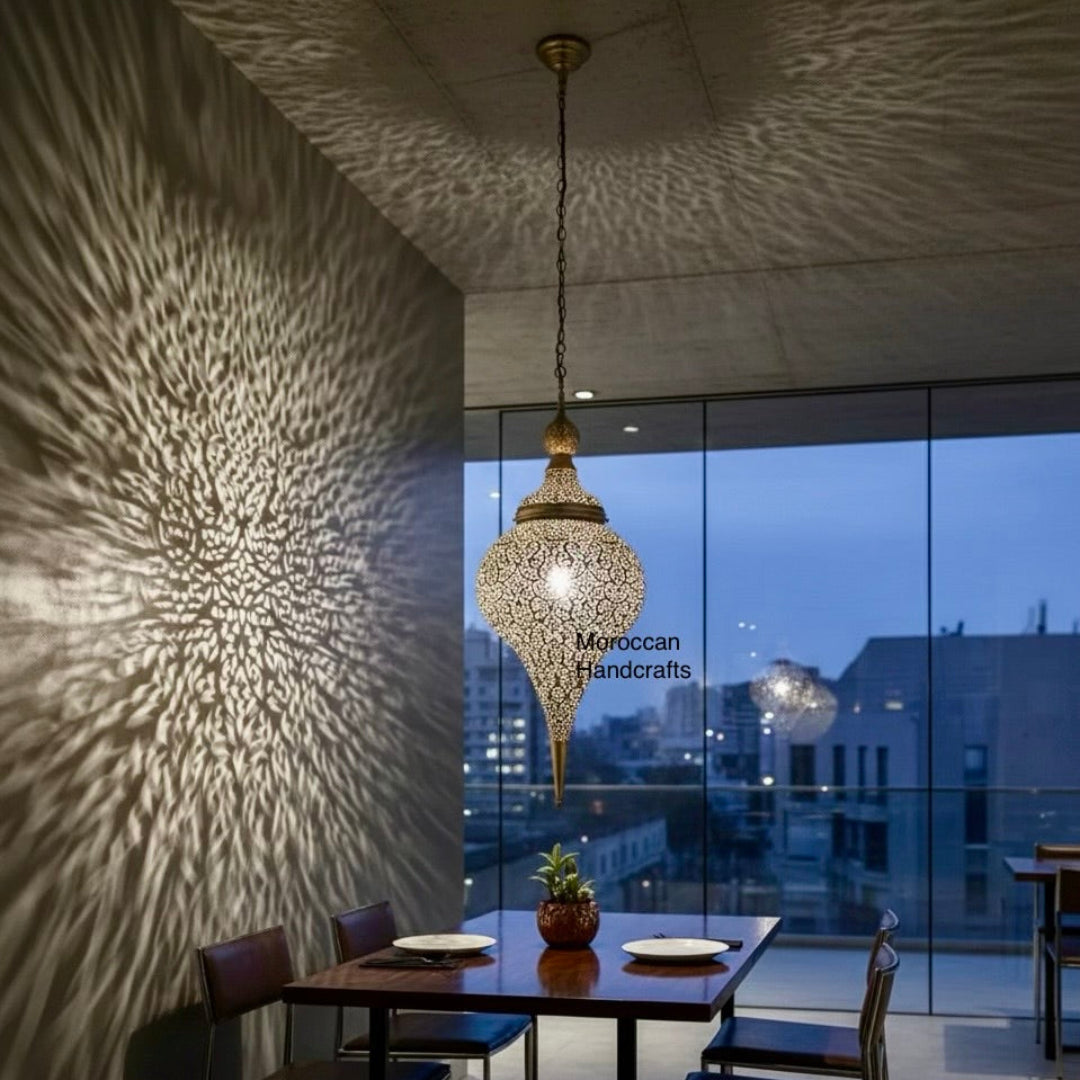 Large teardrop-shaped Moroccan brass lantern hanging in a modern hotel lobby, warm ambient lighting