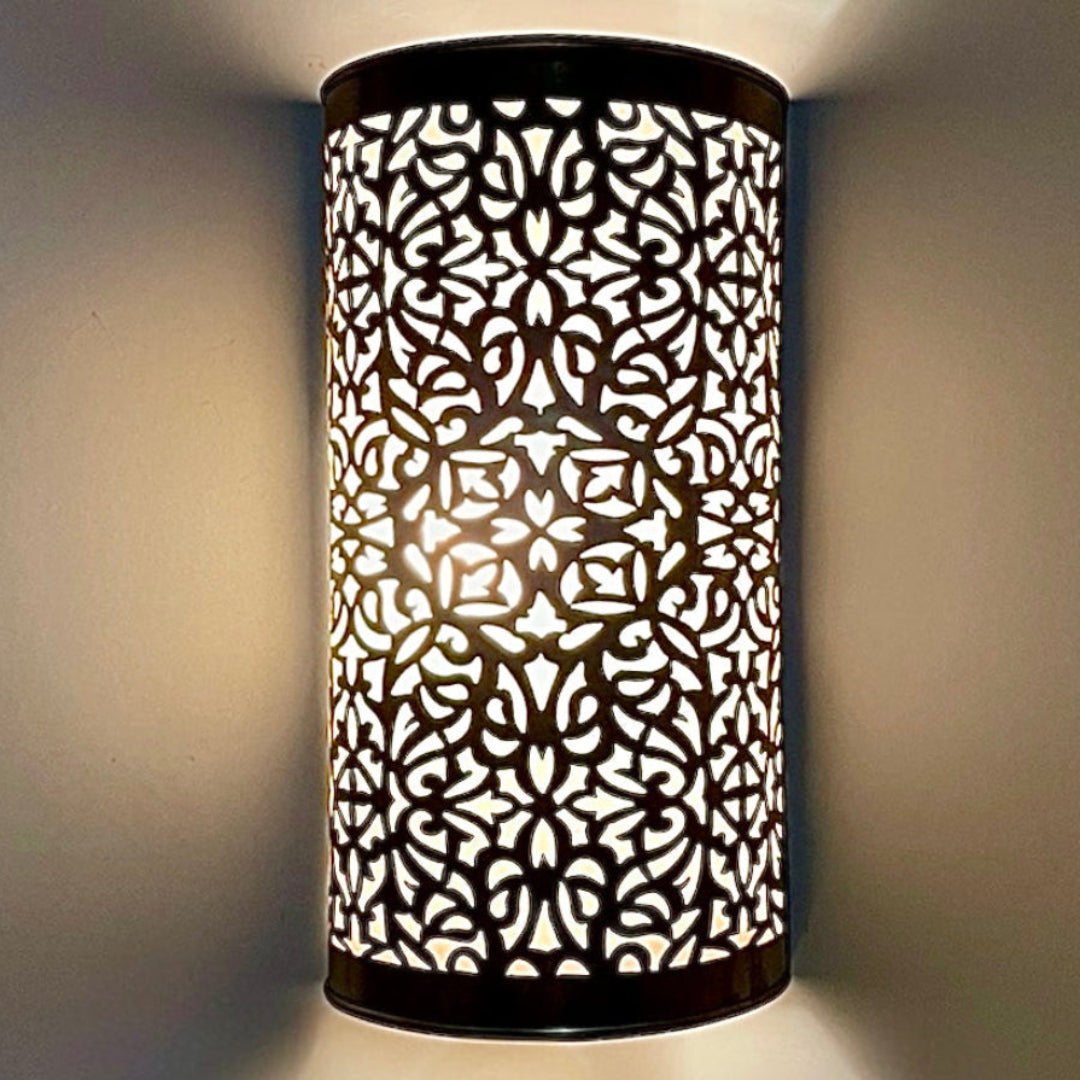 Close-up of an intricate handmade brass wall sconce casting beautiful decorative light patterns.