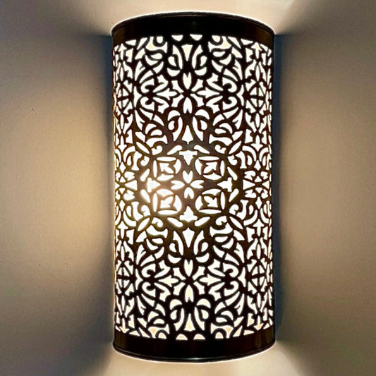 Close-up of an intricate handmade brass wall sconce casting beautiful decorative light patterns.