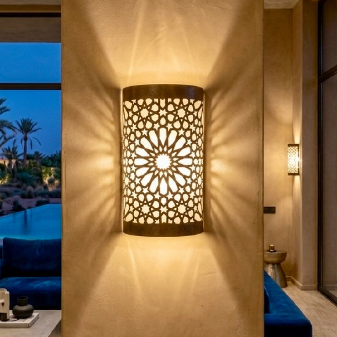 Elegant Moroccan wall lamp made of hammered brass casting a soft golden glow on a textured wall, perfect for ambient home decor.