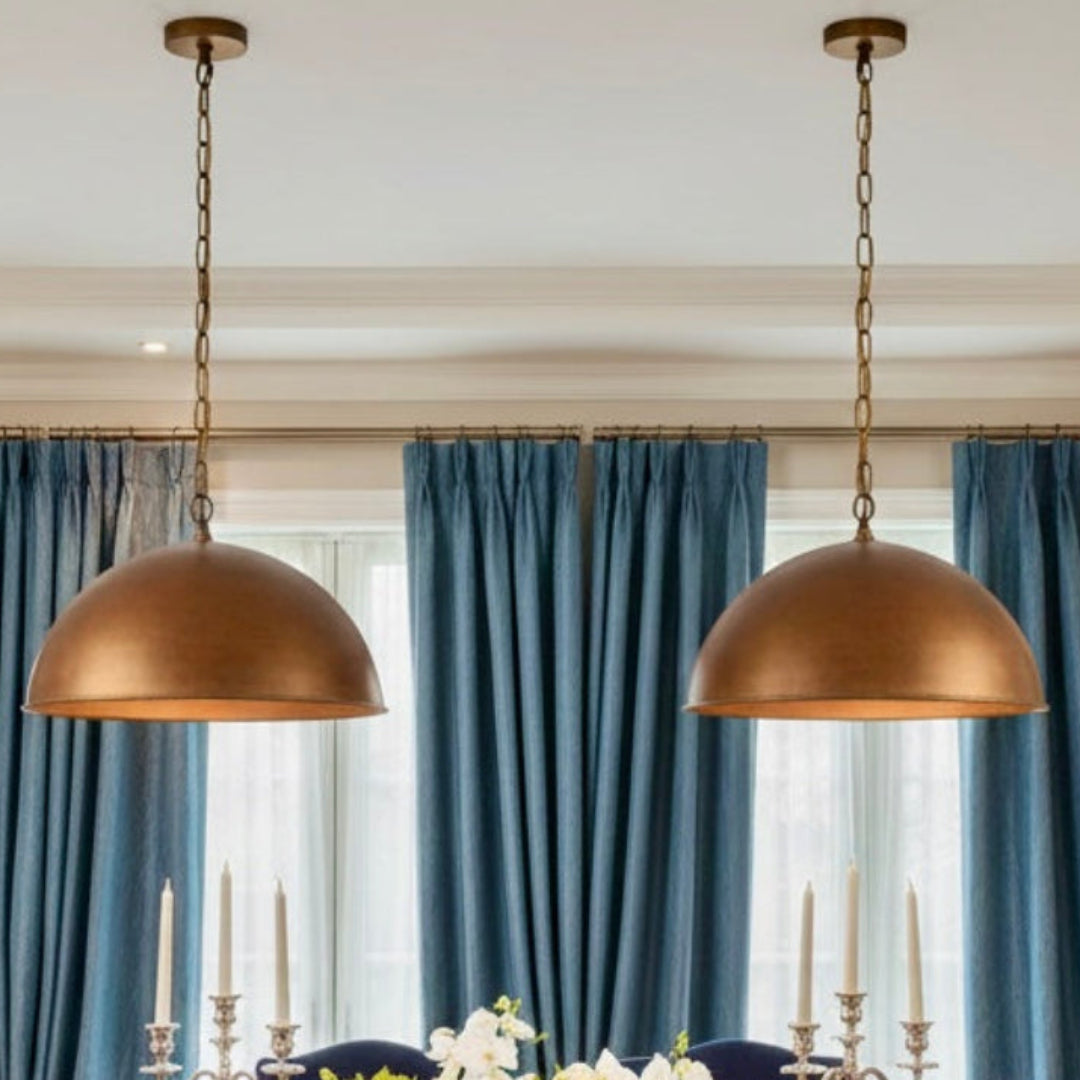 Artisanal Moroccan copper dome lamp in a farmhouse-style dining room with a wooden table and woven chairs.