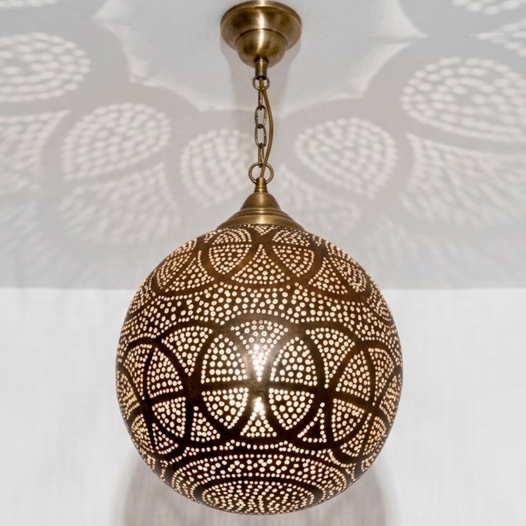  A close-up view of an authentic, handmade Moroccan brass pendant lamp with intricate geometric carvings and high-quality vintage brass finish.