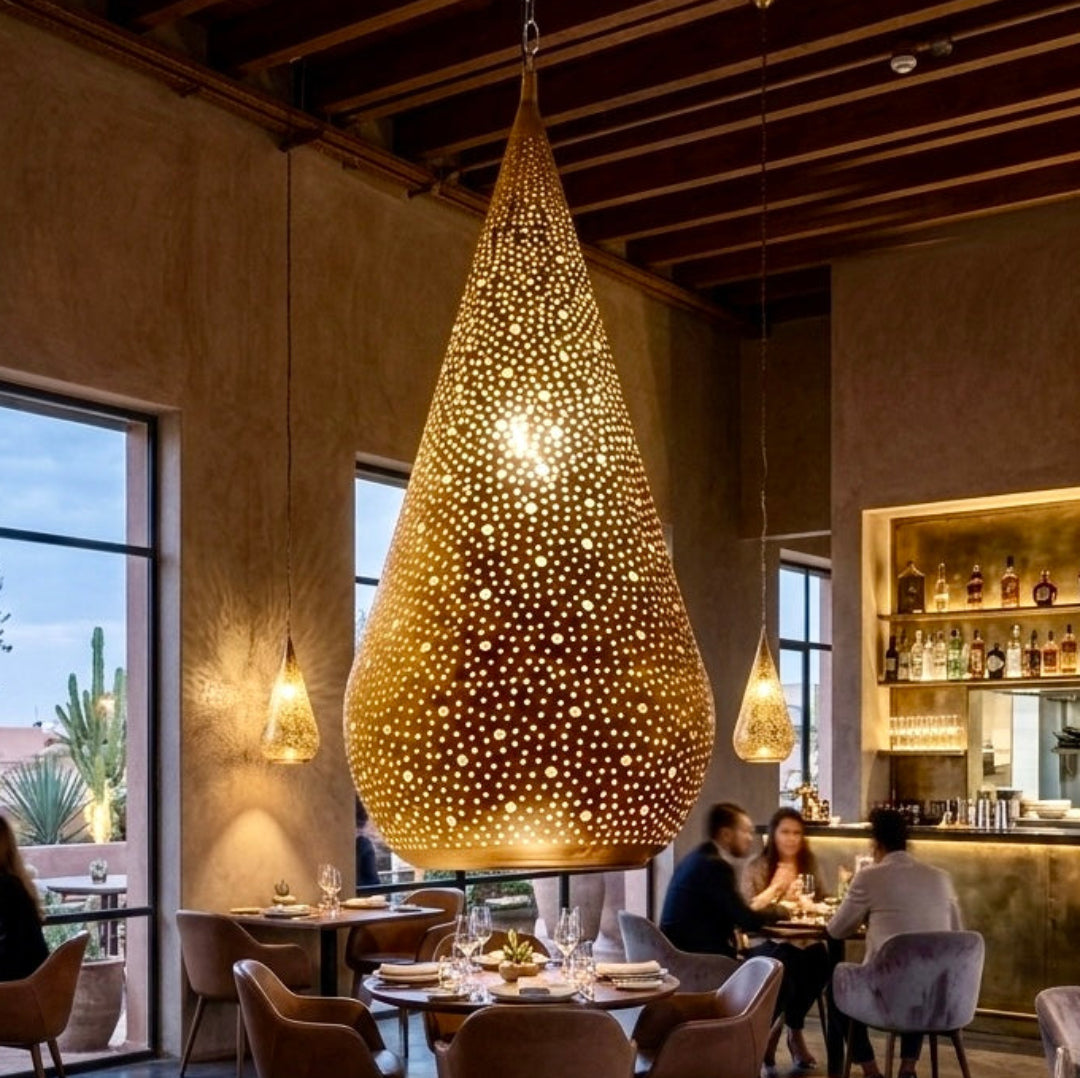  Large teardrop Moroccan brass pendant lamp hanging in a luxury restaurant interior with warm ambient lighting.