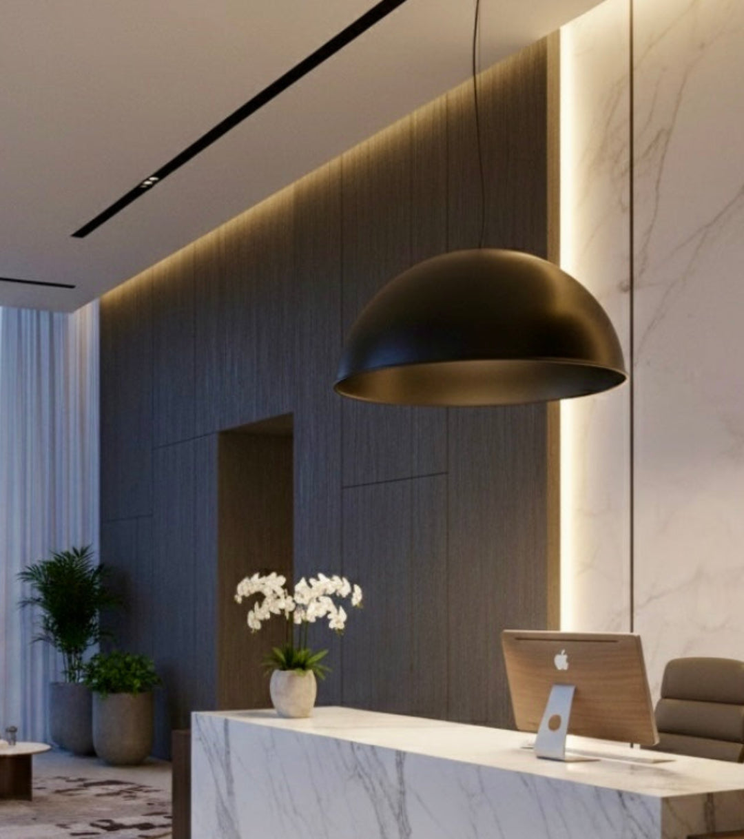 Modern Moroccan dome lamp in black brass hanging over a white marble reception desk in a high-end lobby.