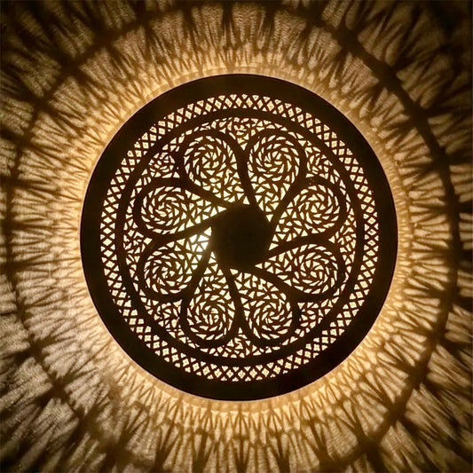  Close-up top view of an illuminated round Moroccan brass ceiling light, showing the detailed artisan craftsmanship and fine geometric fretwork.