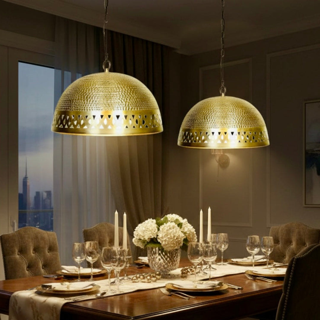  Two large gold-toned Moroccan dome lamps providing warm ambient lighting over a classic wooden dining table with tufted chairs.