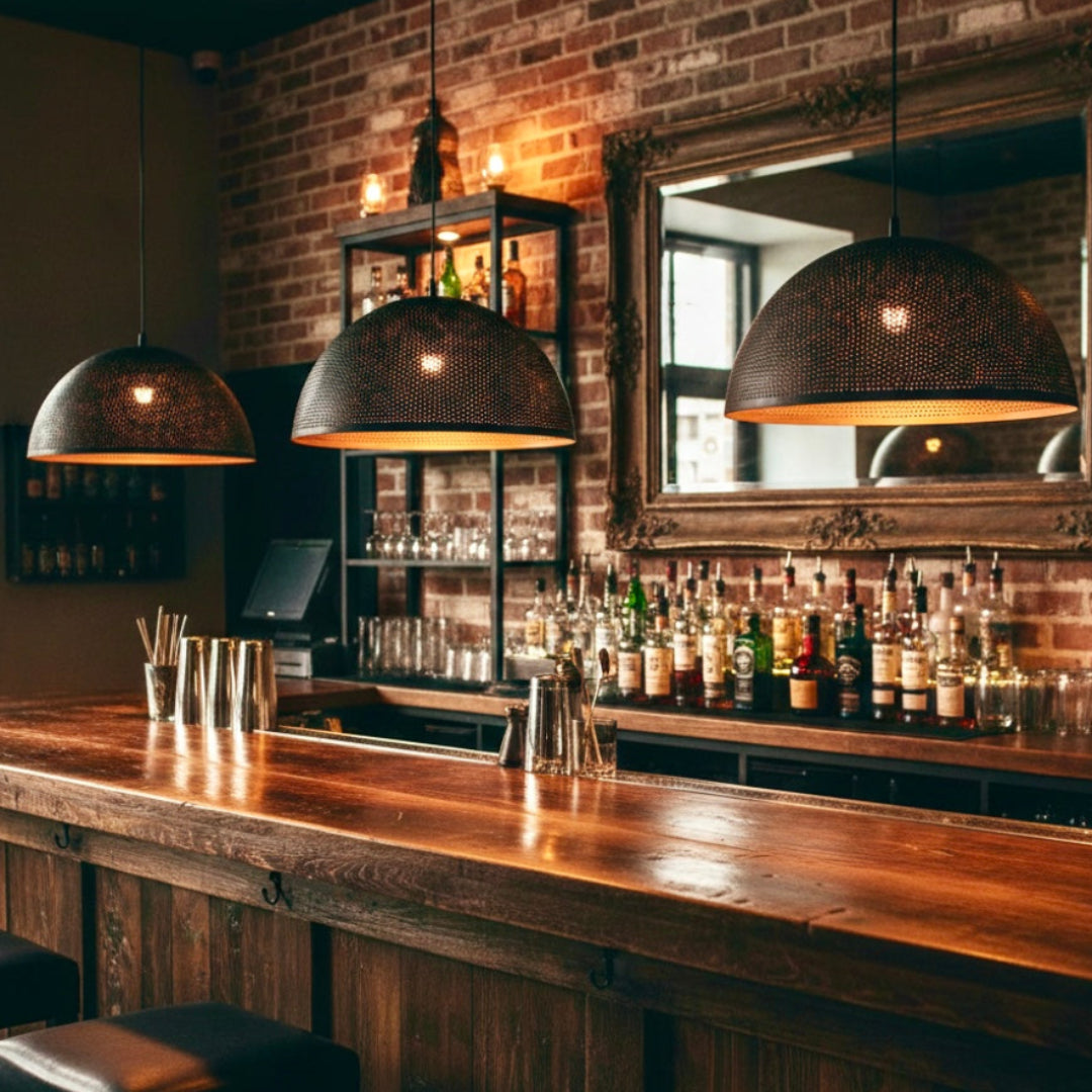 Two large dome-shaped brass pendant lights providing warm ambient lighting in a sophisticated dining room with blue velvet seating.