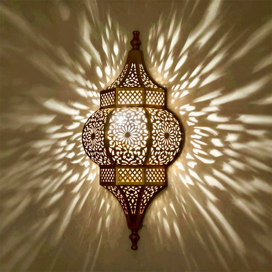 Close-up of a brass wall sconce illuminated, showing the sharp and dramatic ambient shadow projections on a neutral wall.