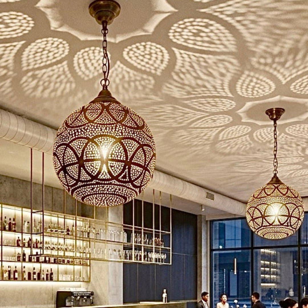 High-end restaurant dining area illuminated by multiple authentic, handmade Moroccan brass pendant lamps, creating an elegant and warm atmosphere.