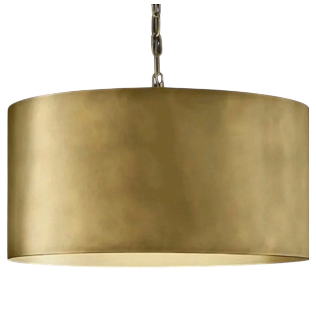 Large modern brass drum light fixture centered over a wooden kitchen island in a bright white contemporary kitchen.