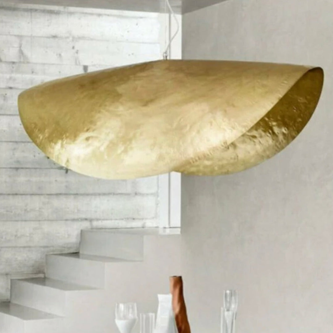 Pair of crescent-shaped Moroccan brass hanging lamps in an elegant high-end dining room with green velvet chairs and a city skyline view.