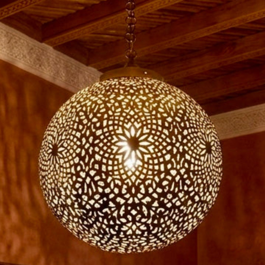 Exotic Moroccan brass chandelier in a warm terracotta bedroom setting with traditional textiles and a hand-carved headboard.