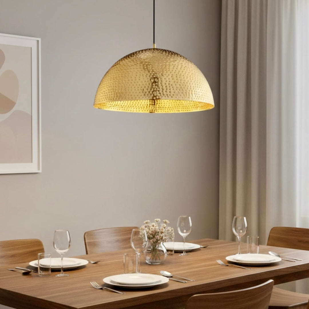 Minimalist dining area featuring a large gold hammered dome chandelier above a natural wood table and chairs.