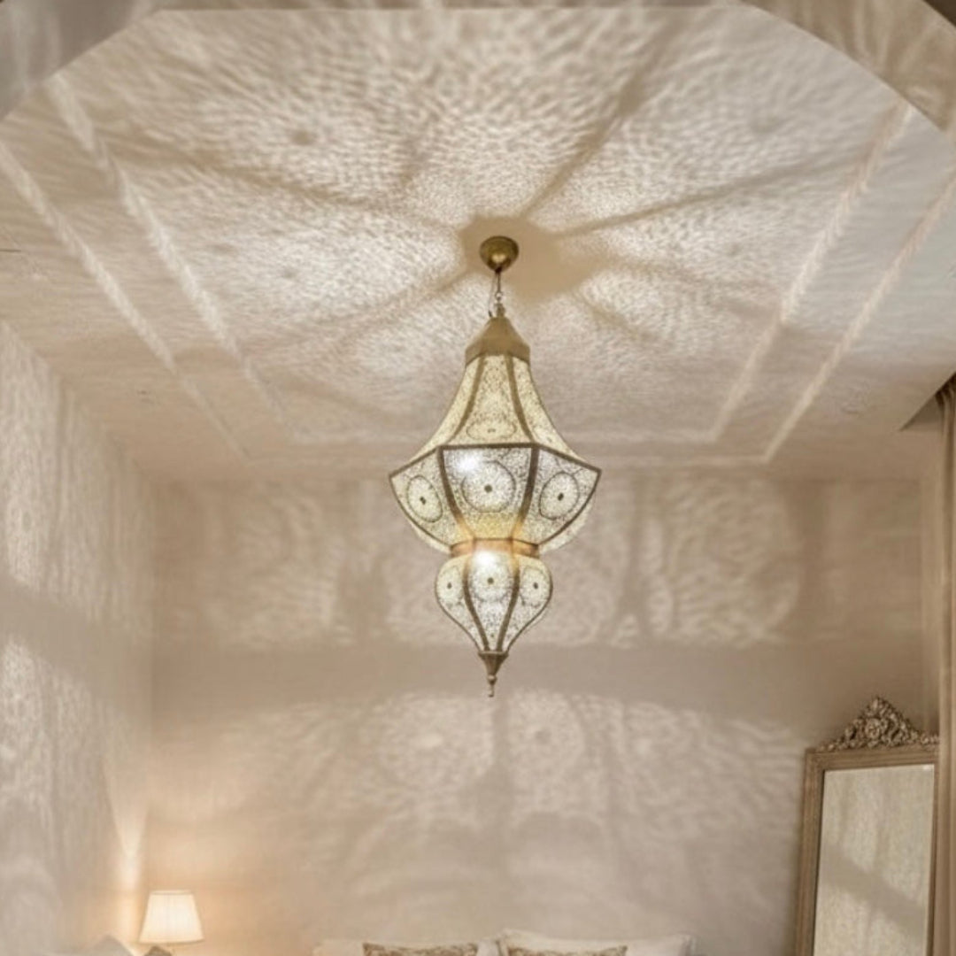 Large handmade Moroccan brass chandelier hanging in a luxury living room, casting intricate geometric shadows on the ceiling.