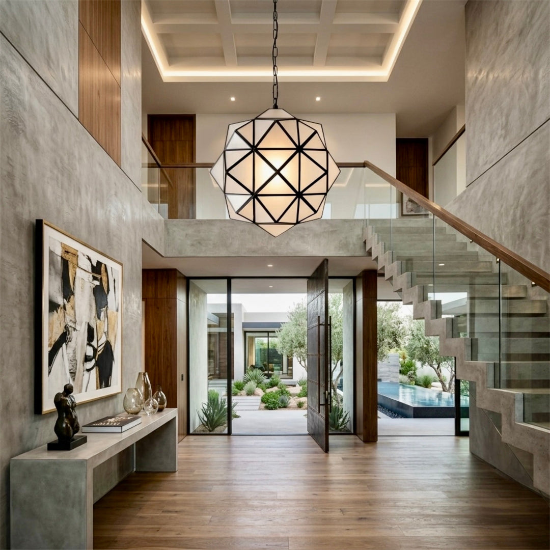 Geometric modern brass and frosted glass star pendant lamp suspended in a luxury high-ceiling entryway with floating stairs